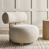 Modern beige chair with wooden legs in a room with paneled walls and a wooden side table.